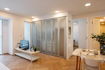 Modern living room with parquet flooring, TV, and dining area