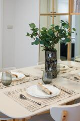 Dining table set with plates, utensils, and a decorative plant