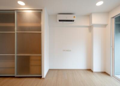 minimalist bedroom with wooden floor, sliding closet doors, air conditioner, and large window