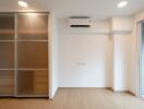 minimalist bedroom with wooden floor, sliding closet doors, air conditioner, and large window