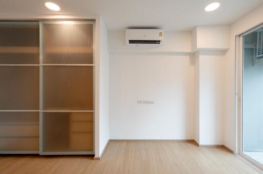 minimalist bedroom with wooden floor, sliding closet doors, air conditioner, and large window