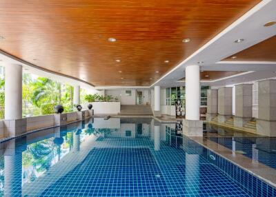 Indoor swimming pool with a wooden ceiling and tiled floor