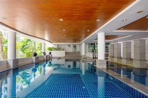 Indoor swimming pool with a wooden ceiling and tiled floor