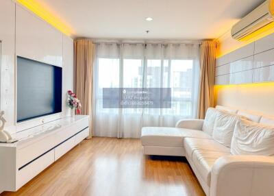 Modern living room with white furniture, wooden flooring, and large windows