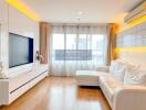 Modern living room with white furniture, wooden flooring, and large windows