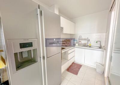 Modern kitchen with stainless steel refrigerator and white cabinets