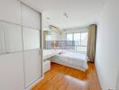 Spacious bedroom with wooden floor, large window, and built-in wardrobe