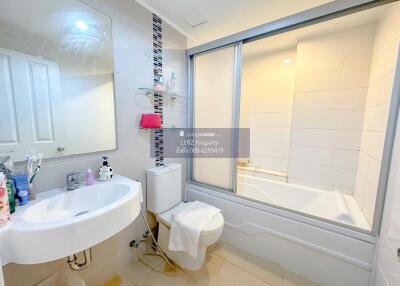 Well-lit modern bathroom with sink, toilet, and bathtub