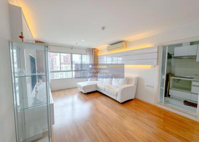 Bright living room with wood flooring, white furniture, and large windows