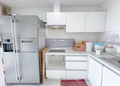 Modern kitchen with white cabinetry and stainless steel refrigerator