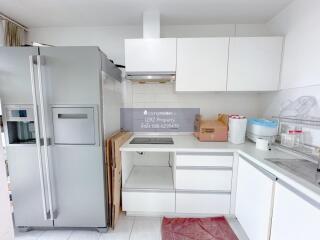 Modern kitchen with white cabinetry and stainless steel refrigerator