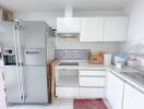 Modern kitchen with white cabinetry and stainless steel refrigerator