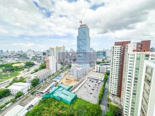 Aerial view of urban area with high-rise buildings, green spaces, and construction site