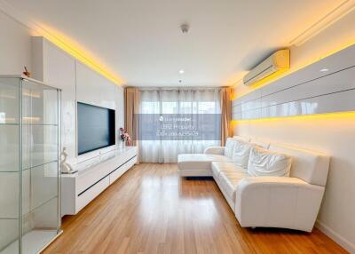 Modern living room with white sofa, hardwood floor, and large TV