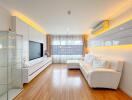 Modern living room with white sofa, hardwood floor, and large TV