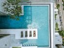 Aerial view of a large pool with lounge chairs and a person sunbathing