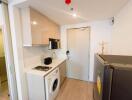 Compact kitchen area with modern appliances and washing machine