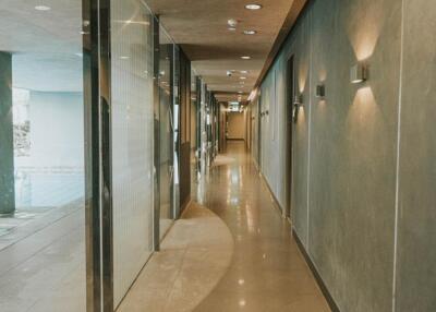 Modern hallway with glass partitions and lit wall sconces