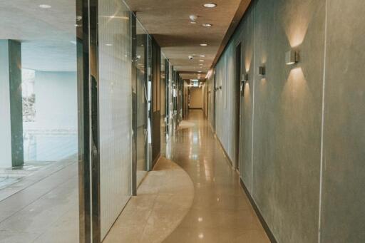 Modern hallway with glass partitions and lit wall sconces