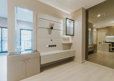 Modern living room with large mirror, glass shelves, and a minimalistic setup.