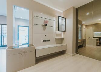 Modern living room with large mirror, glass shelves, and a minimalistic setup.