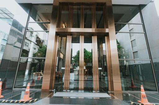 Entrance of a modern building with glass walls and golden accents