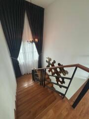 A well-lit staircase featuring wooden steps, a modern railing, and a hanging chandelier