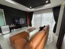 Modern living room with brown leather couch, TV, and large window with curtains