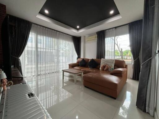 Modern living room with a large brown sofa and panoramic windows