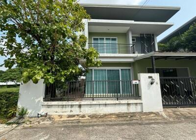 Front view of a modern two-story house with a balcony and gated entrance