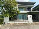 Front view of a modern two-story house with a balcony and gated entrance