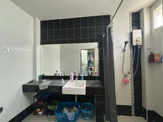 Modern bathroom with black and white tiles, a large mirror, vanity, and shower area