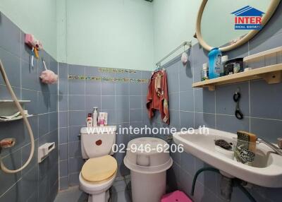 A compact bathroom with toilet, sink, and a variety of toiletries