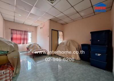 A room with a bed, covered furniture, and storage boxes