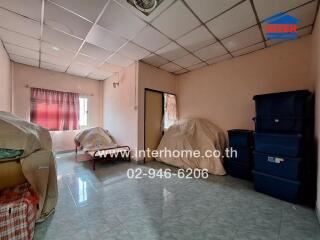 A room with a bed, covered furniture, and storage boxes