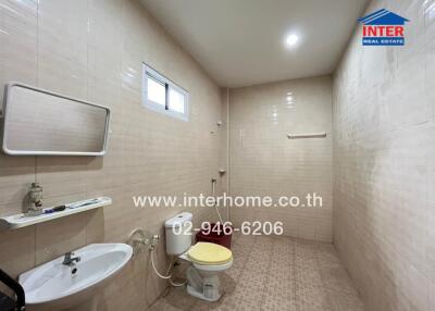 A bathroom with a sink, toilet, mirror, and wall shelf.