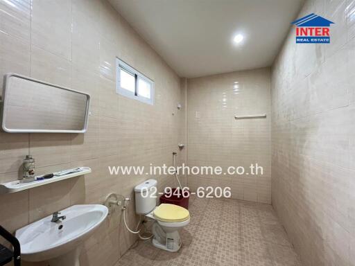 A bathroom with a sink, toilet, mirror, and wall shelf.