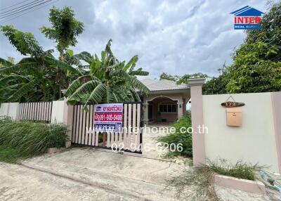 Photo of the front exterior of a house with a sign listing the property for sale.