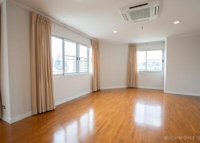 Spacious living room with wooden flooring and large windows with curtains