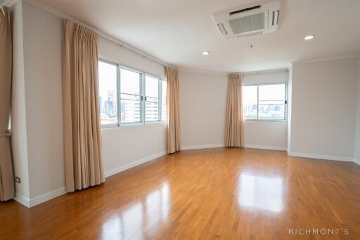 Spacious living room with wooden flooring and large windows with curtains