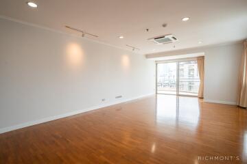 Spacious and well-lit living room with wooden flooring and large windows