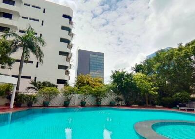 Outdoor swimming pool area with trees and nearby buildings