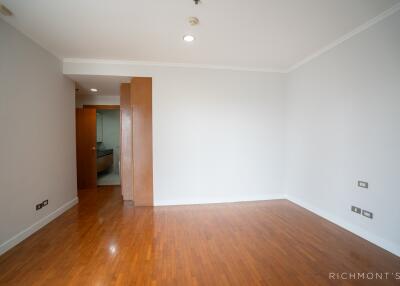 Empty bedroom with wooden flooring and a partially open door