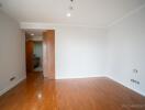 Empty bedroom with wooden flooring and a partially open door