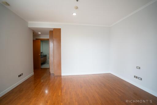 Empty bedroom with wooden flooring and a partially open door