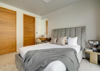 Well-lit bedroom with a cozy bed, wooden doors, and modern furnishings