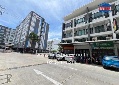 Exterior view of multi-story residential and commercial buildings with parking area