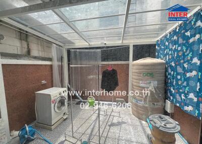 outdoor laundry area with washing machine and water tank