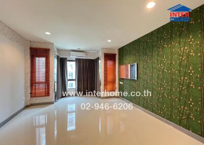 Spacious living room with large windows, modern lighting, and a nature-themed accent wall