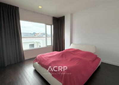 Spacious bedroom with a large window and dark curtains